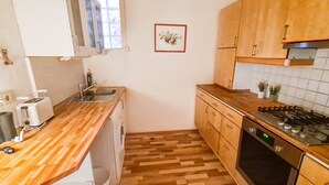 A compact kitchen with wooden cabinets, a built-in oven, and a wooden countertop.