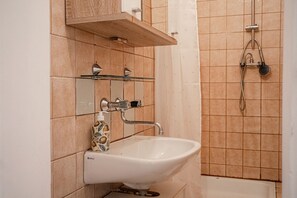 Un bagno con lavandino bianco, uno specchio e una doccia.