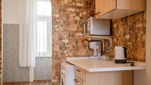 A compact kitchen with a stone backsplash, a washing machine, a coffee maker, and wooden cabinets. - Cheerful 2BR Apartment - Suitable for Longstays (Vienna)