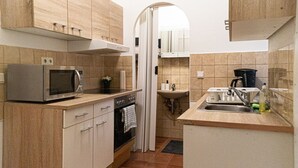 Une cuisine de taille réduite équipée d’un four à micro-ondes, d’un four traditionnel, d’un évier et de placards.