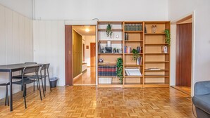 A room with a wooden herringbone floor, a dining table with chairs, a bookshelf, and a sofa. - Vienna's Finest: Spacious Apt. w/2+1 Configuration (Vienna)