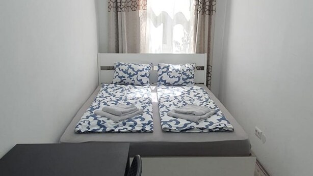 A double bed with a patterned bedspread, a bedside table, and a chair. - Enkplatz U3 Getaway: Affordable 5-BR Apartment (Vienna)