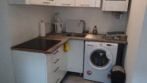 A compact kitchen with a washing machine, a sink, and a coffee maker. - Enkplatz U3 Getaway: Affordable 5-BR Apartment (Vienna)
