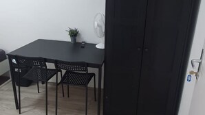 A room with a black table, four black chairs, a white fan, a small potted plant, and a closed black door. - Enkplatz U3 Getaway: Affordable 5-BR Apartment (Vienna)