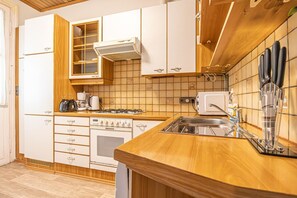 A kitchen with white cabinets, a wooden countertop, a stove, a sink, and a coffee maker.