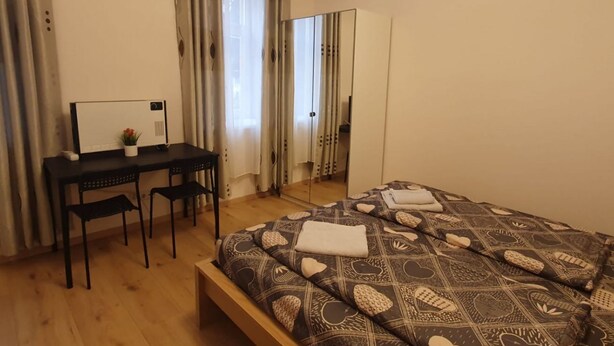 A bedroom with a bed, a desk, two chairs, a mirror, and a wardrobe. - Relaxing 2-Bed Apartment for Extended Visits (Vienna)
