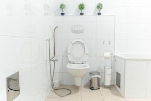 A modern bathroom with a toilet, bidet, and hand dryer.