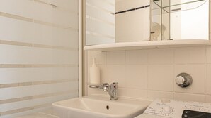 A bathroom with a sink, mirror, and a washing machine.
