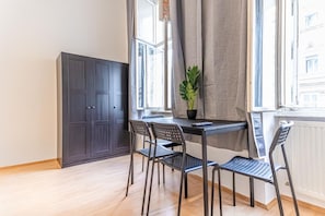 Un coin repas comprenant une table, des chaises, une plante en pot et un meuble sombre.