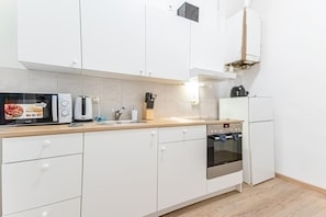A modern kitchen with white cabinets, a built-in oven, a coffee maker, and a toaster.