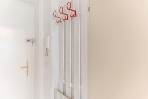 A white door with a gold handle, a white radiator, and a red coat hook on the wall.