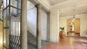 A spacious lobby with a staircase, large columns, and a tiled floor. - Lemon Tree One Bedroom with Balcony (Florence)