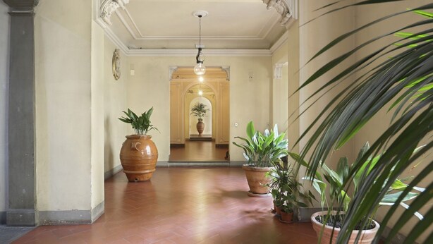 A hallway with a tiled floor, large potted plants, and a decorative ceiling light. - Lemon Tree One Bedroom with Balcony (Florence)