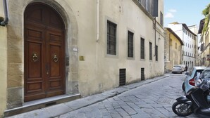 A cobblestone street with a large wooden door and a motorcycle parked on the right. - Lemon Tree One Bedroom with Balcony (Florence)
