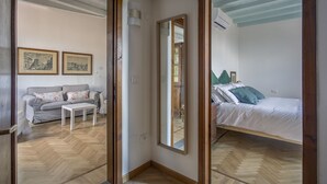 A room with a bed, a sofa, a small table, and a mirror. - Maggio In Florence (Firenze)