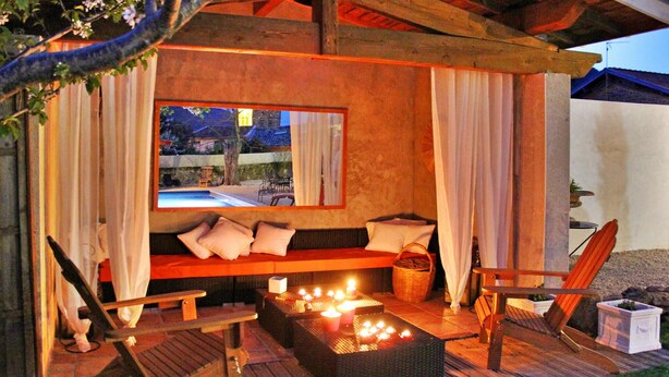 Un área de estar al aire libre con un sofá, cojines y una mesa con velas.