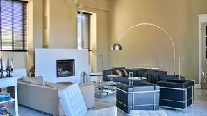 Una sala de estar moderna con sofá, sillones, una mesita de centro y chimenea.