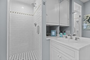 A modern bathroom with a walk-in shower, white tiled walls, a large mirror, and a white vanity with a sink. - Two Bed, Two Bath, two blocks from water, downtown Newport summer rental.  (Newport)