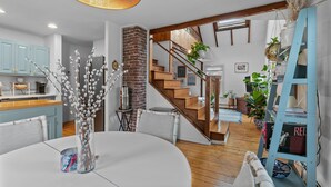 Une cuisine moderne avec des meubles de couleur bleu clair, un mur en briques et un escalier en bois menant à une mezzanine.