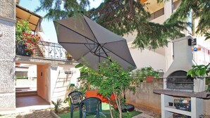 A courtyard with a patio area, outdoor seating, and a barbecue grill. - Holiday apartment with air conditioning (Fažana)