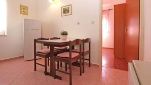Une cuisine compacte comprenant une table à manger, des chaises, un réfrigérateur et une plante en pot.