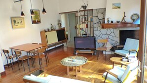 Ein Wohnzimmer mit Fernseher, Holzmöbeln, einer Steinwand und einem Kamin.