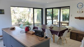 Eine moderne Küche mit einer Holztheke, großen Fenstern und Blick ins Freie.