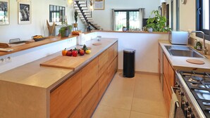 A modern kitchen with wooden cabinets, a central island, a stove, and a sink. - Stunning home in Maillane with WiFi (Maillane)