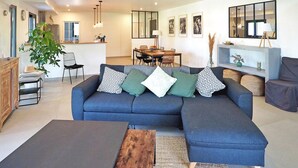 A modern living room with a blue sectional sofa, a wooden coffee table, and a dining area with a table and chairs. - Stunning home in Maillane with WiFi (Maillane)