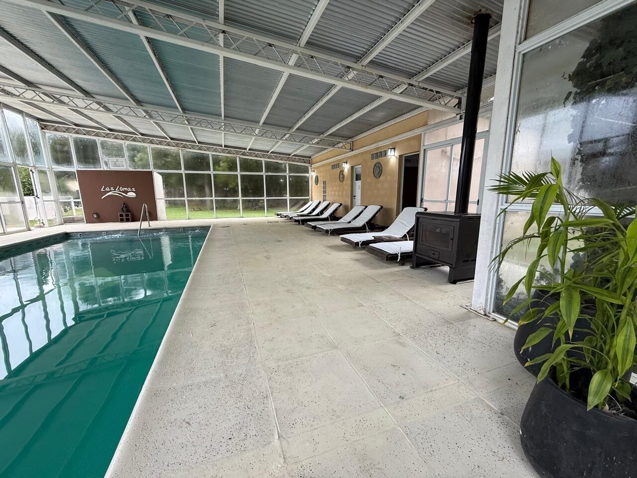 Zona de piscina techada con sillones de descanso y un letrero que dice 'Las Lomitas'.