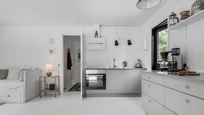 A modern, minimalist kitchen with white cabinetry, a built-in oven, and a coffee machine.