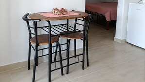 A dining area with a round table, chairs, and a pink placemat. - Studio 'Gorgona' with sea view, Wi-Fi and air conditioning (Loutra)