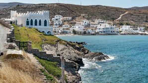A coastal town with white buildings, a castle-like structure, and a rocky shoreline. - Studio 'Gorgona' with sea view, Wi-Fi and air conditioning (Loutra)