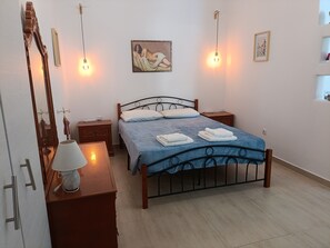 A bedroom with a bed, bedside tables, a dresser, a mirror, and wall-mounted lights.