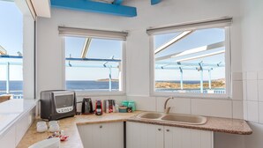 Eine Küche mit Meerblick, einem Toaster, einer Spüle und einem Fenster mit Blick auf einen Steg.