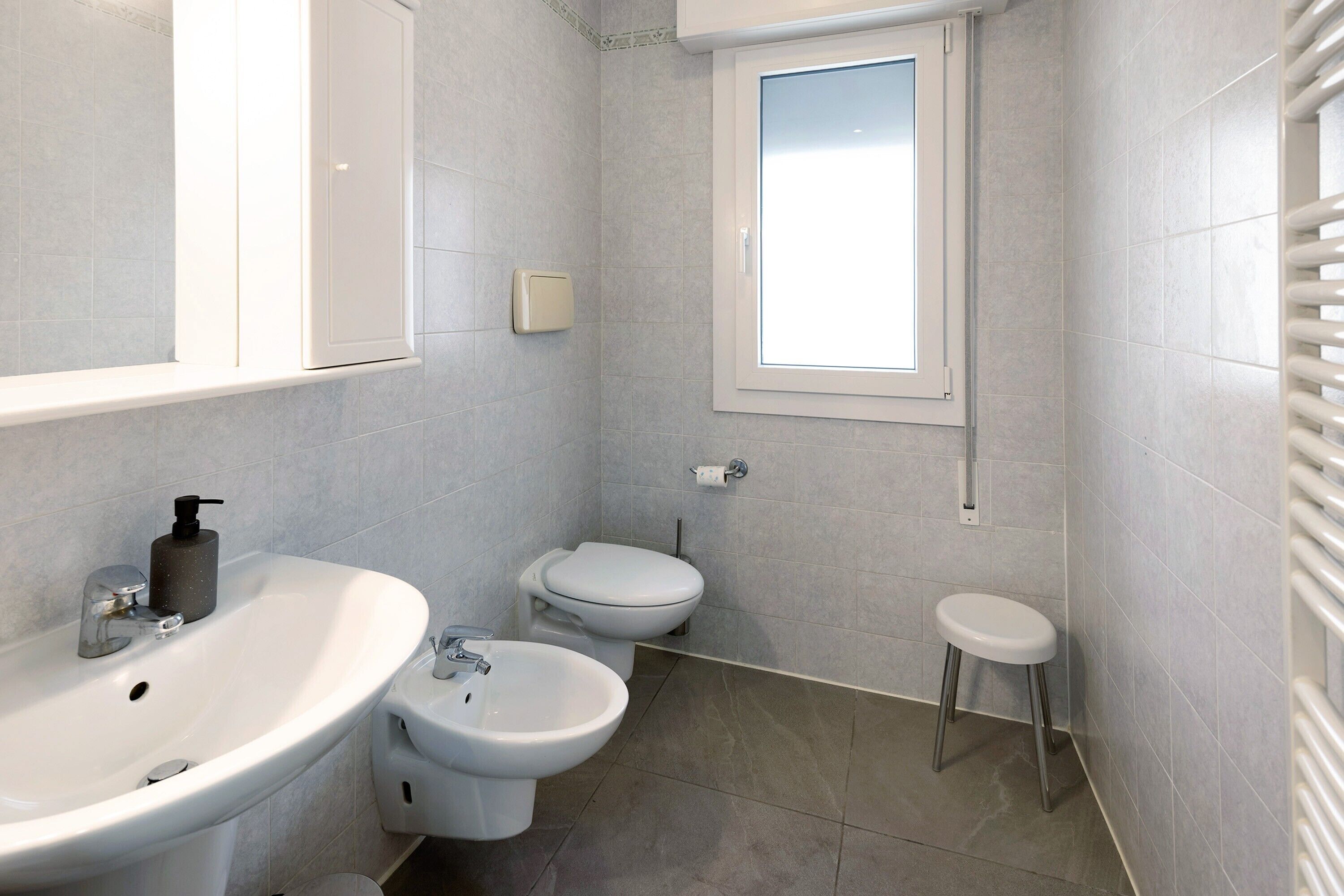 Ein Badezimmer mit Waschbecken, Bidet, Toilette und einem Fenster.