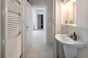 Une salle de bain avec un lavabo blanc, un miroir et un porte-serviettes.
