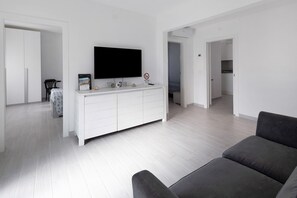 Un salon moderne avec un meuble de rangement blanc pour l’équipement audiovisuel, un téléviseur à écran plat et un canapé.