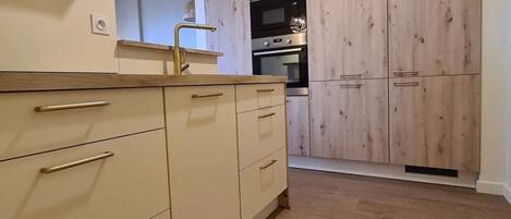 A kitchen with wooden cabinets, a stainless steel oven, and a countertop.