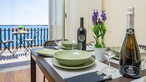 Una mesa de comedor dispuesta con platos, vasos, una botella de vino y una planta en maceta.