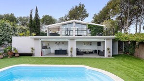 Une maison moderne à deux étages, dotée d’une piscine, d’un patio couvert et d’un jardin aménagé.