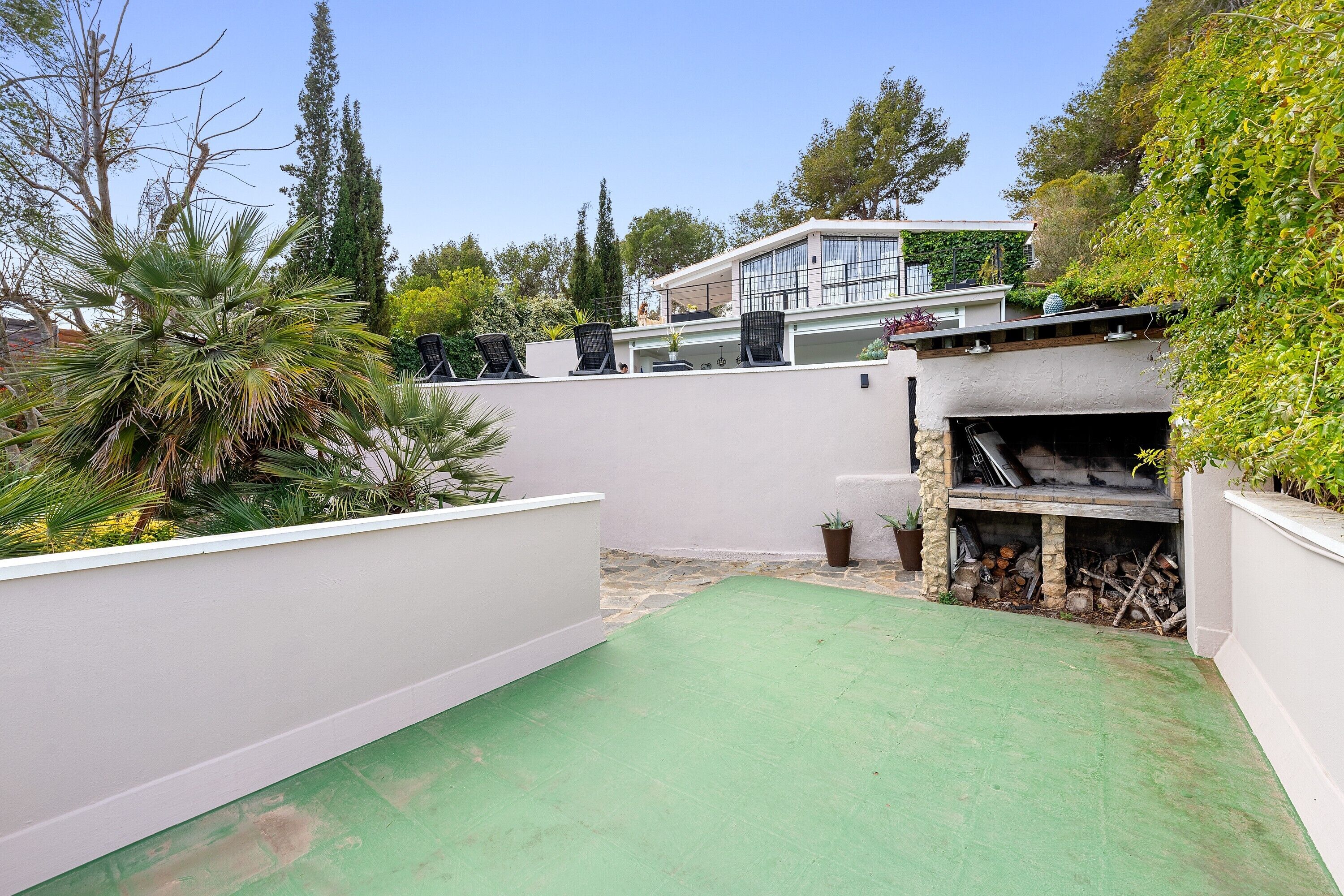 Un patio sul tetto con superficie verde, un camino in pietra e un muro bianco.