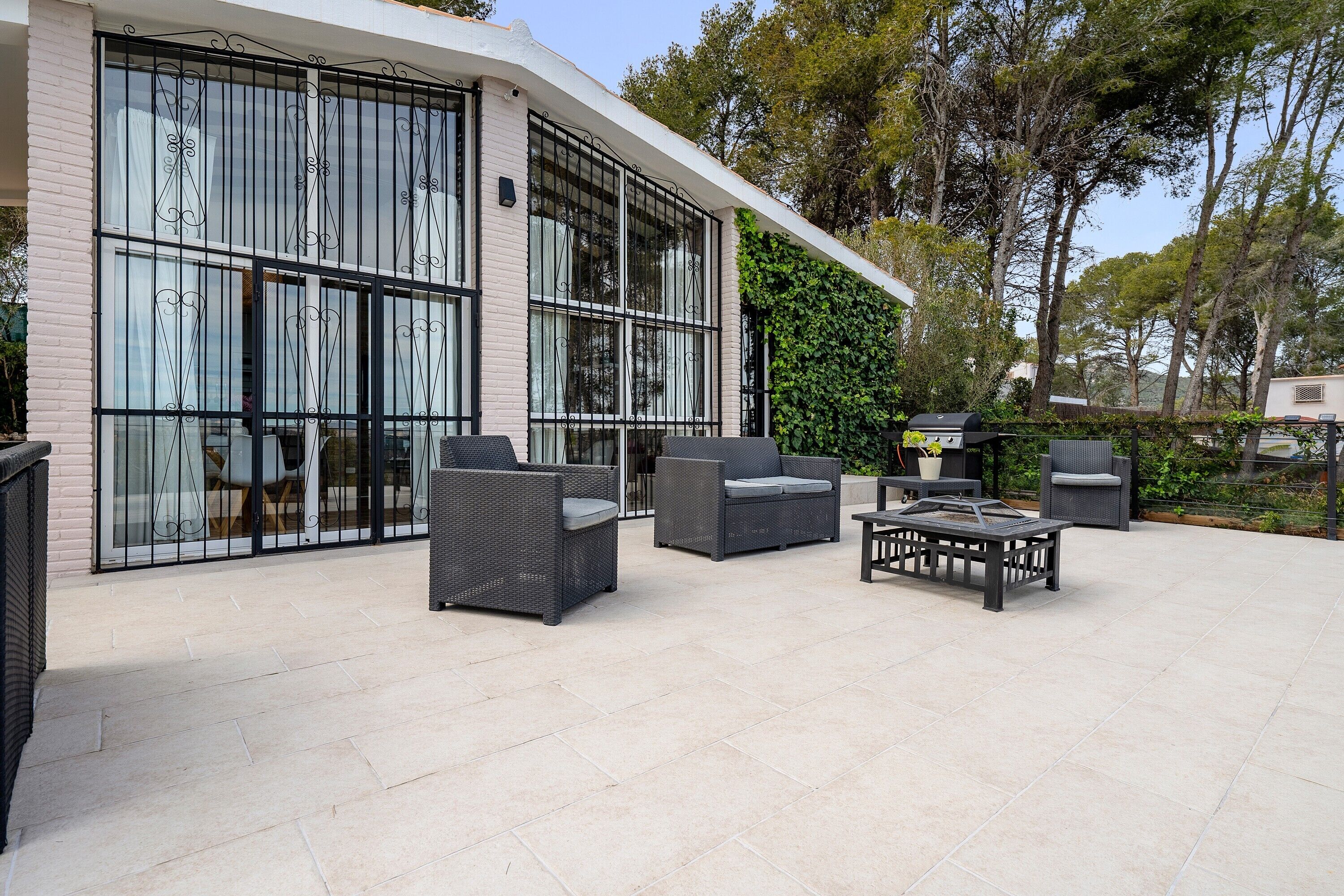 Un edificio moderno con ampie finestre e un patio arredato con mobili da esterno.