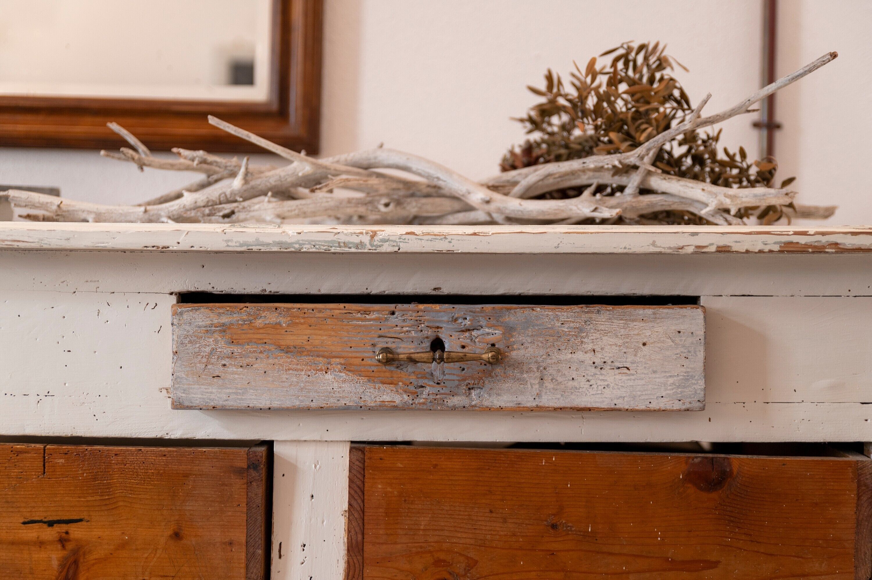 Un meuble en bois rustique, doté d’une finition vieillie, d’une petite poignée en laiton et d’un tiroir.
