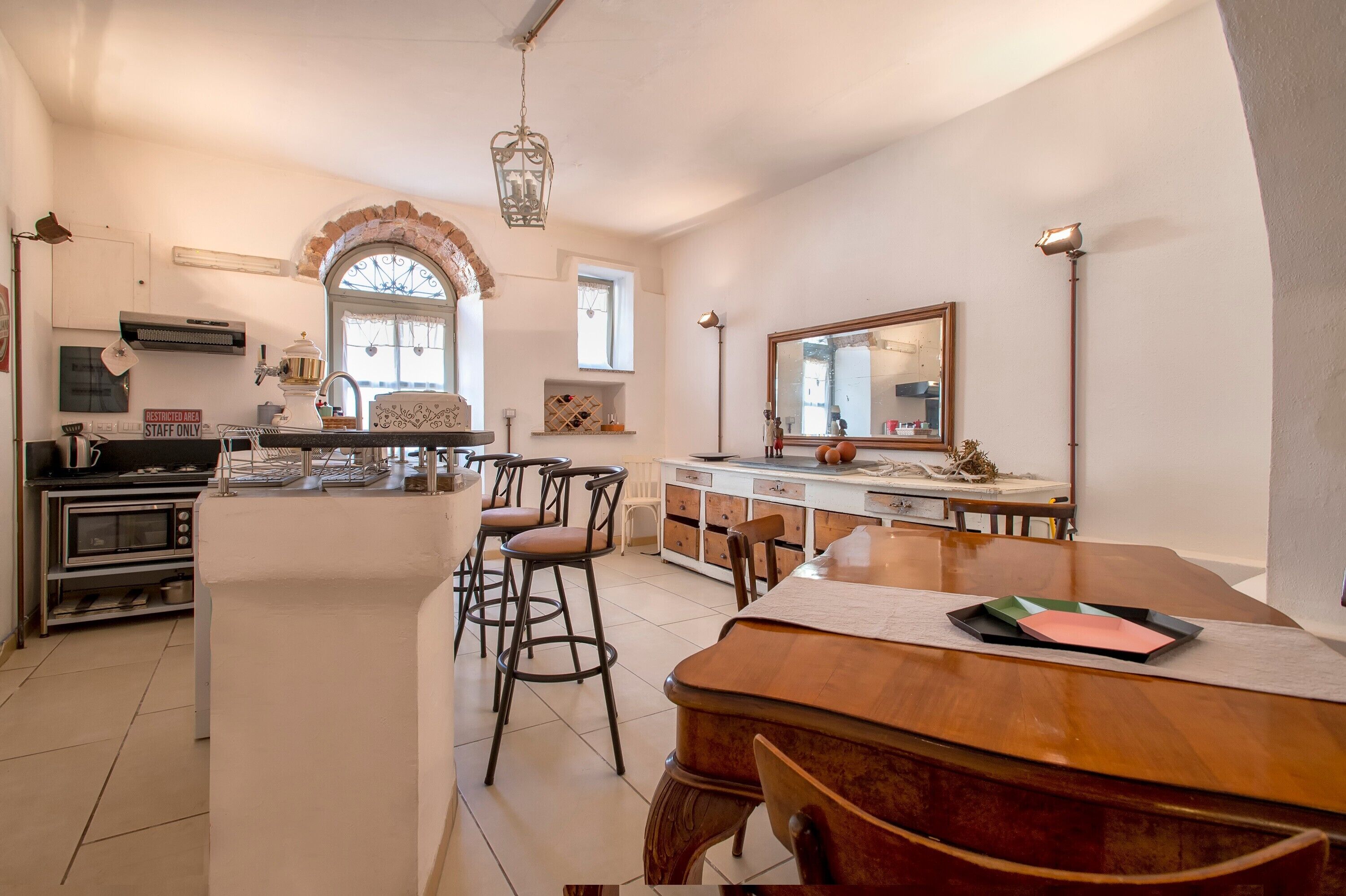 A kitchen with a central island, bar stools, a dining table, and a large mirror.