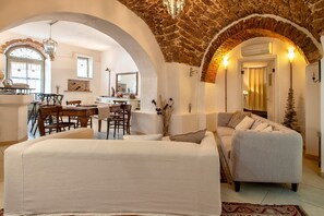 Una sala de estar con techo de piedra, un sofá, un comedor con sillas y una escalera.