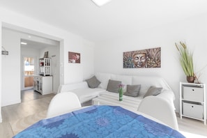 Una sala de estar moderna con un sofá blanco, una mesa de centro y un cuadro en la pared.