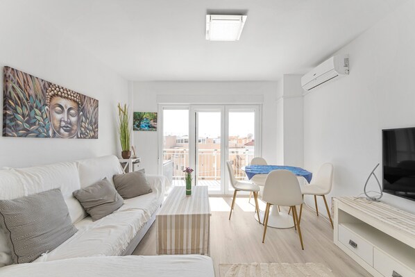 A modern living room with a sofa, a coffee table, a TV, and a balcony with a view.