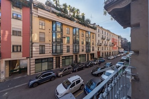 A multi-story building with balconies, parked cars, and a clear sky.