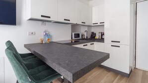 Eine moderne Küche mit weißen Schränken, einer grauen Arbeitsplatte und einer eingebauten Mikrowelle.